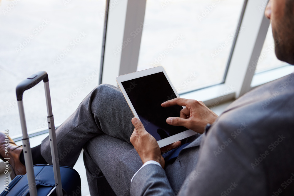 © Monkey Business - Businessman Using Digital Tablet In Airport Departure Lounge