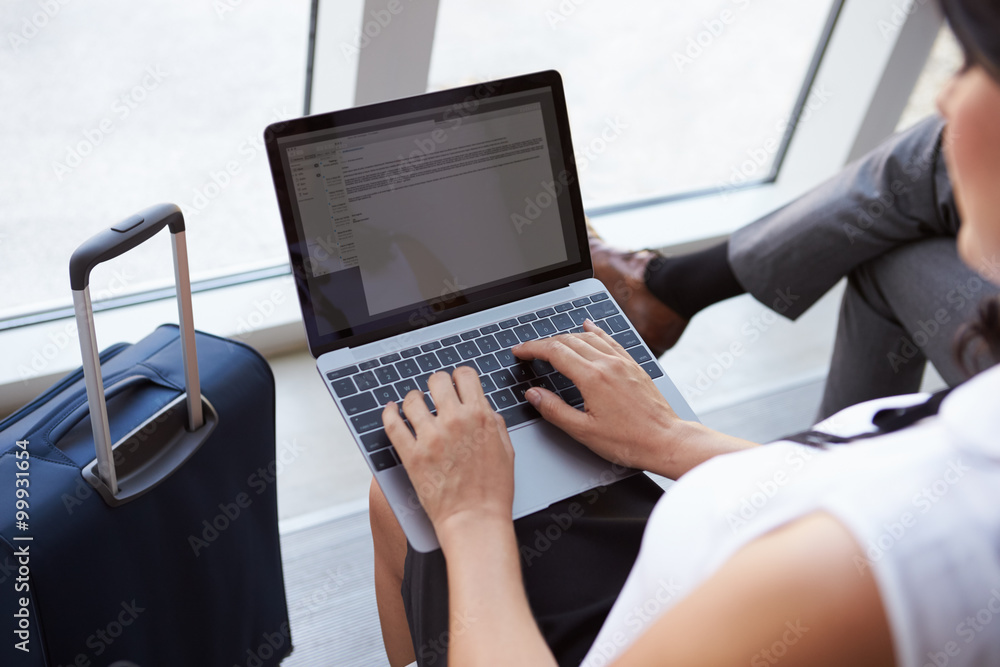 © Monkey Business - Businesswoman Using Laptop In Airport Departure Lounge