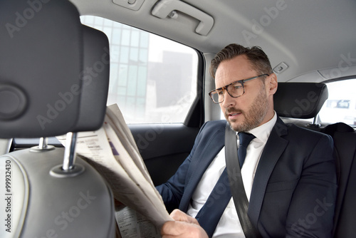 Businessman in taxi cab reading newspaper © goodluz