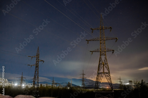 Power transmission line support structure at night against background with mountains