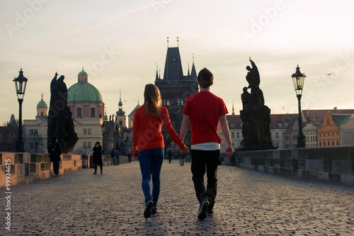 Loving couple walking down the Charles Bridge in Prague at sunset