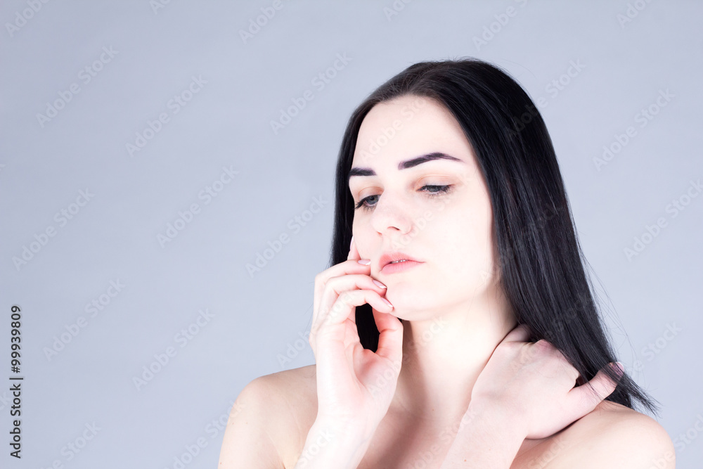 Brunette woman touching her cheek by hand and looking down. Beauty concept Brunette woman touching her cheek by hand and looking down. Beauty concept