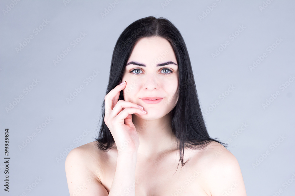 Woman with dark hair smiling and touching her cheek by hand. Beauty concept Woman with dark hair smiling and touching her cheek by hand. Beauty concept