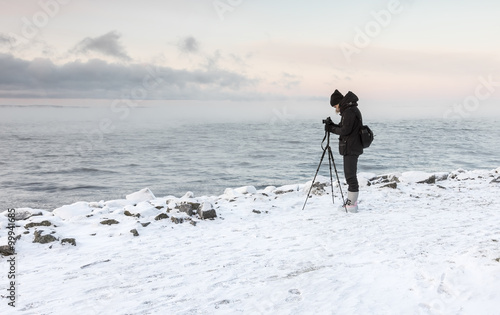 Woman photographer next to lake at winter time
