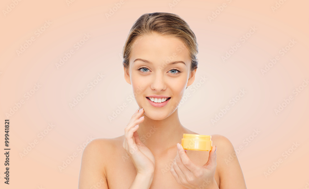 happy young woman applying cream to her face happy young woman applying cream to her face