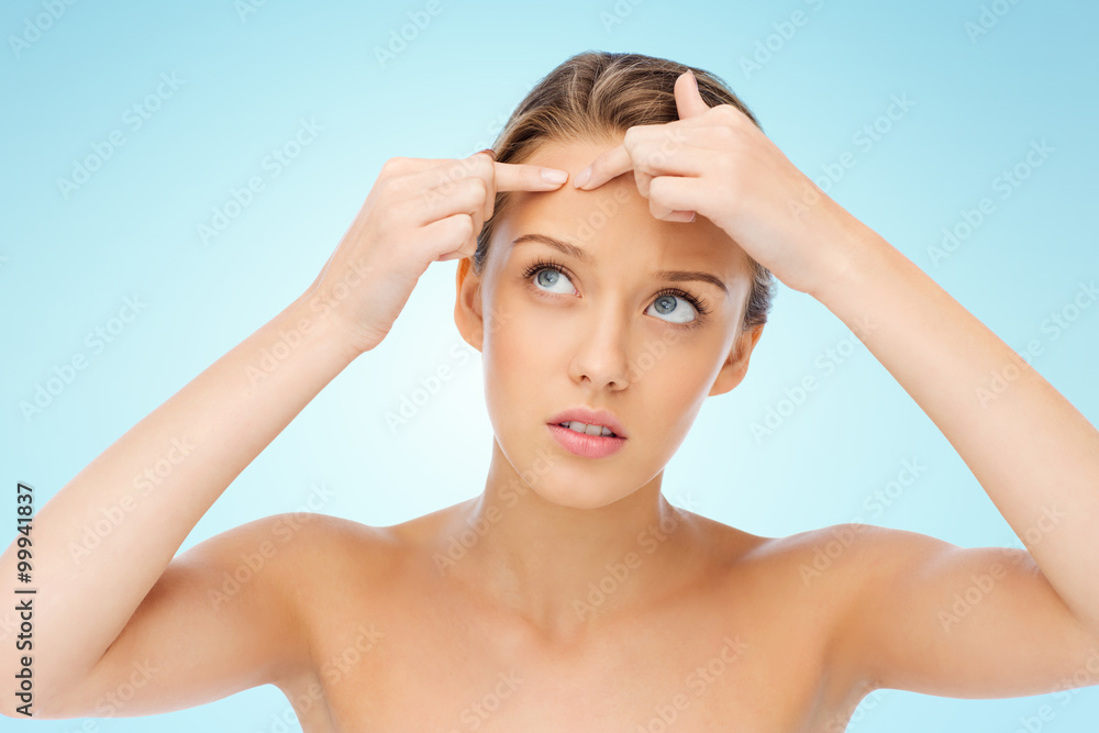 Naklejka premium young woman squeezing pimple on her face