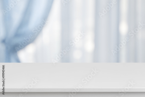 White table on defocuced window with blue curtain background