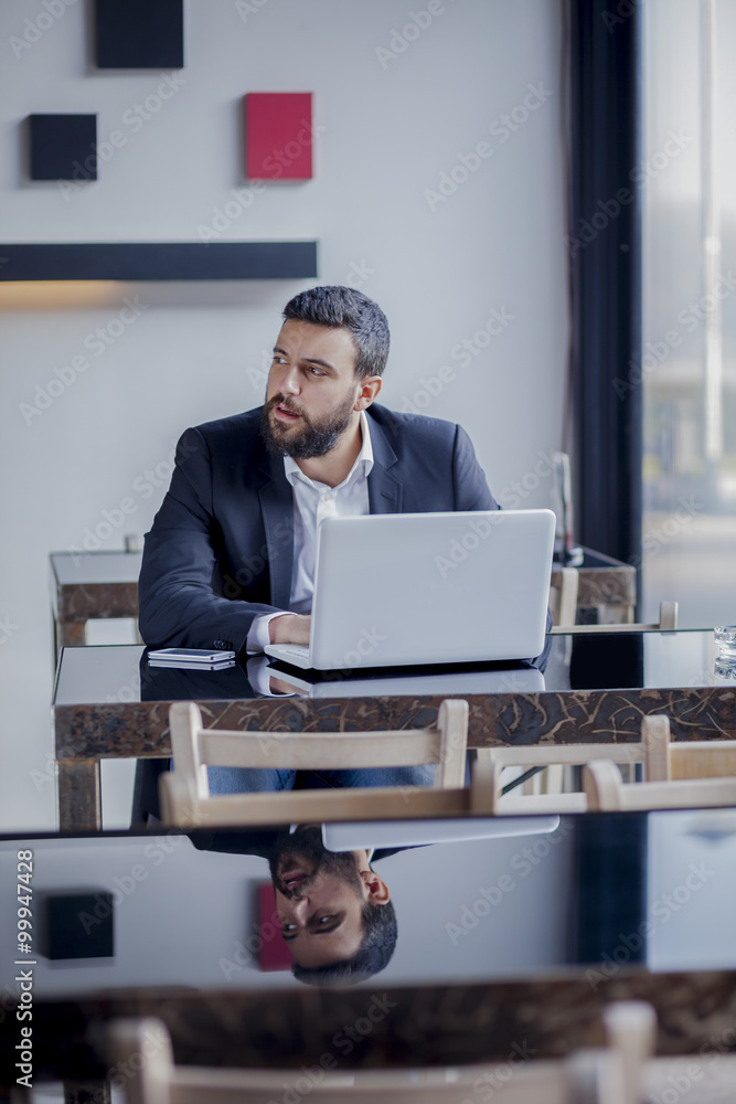 Handsome business man sitting in coffee shop and working on his laptop,shallow depth of field Handsome business man sitting in coffee shop and working on his laptop,shallow depth of field