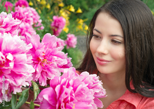 Young woman looking at flowers peonies