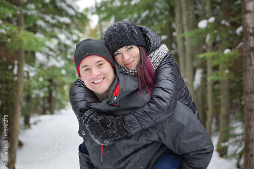 Winter couple piggyback in snow smiling happy and excited. 