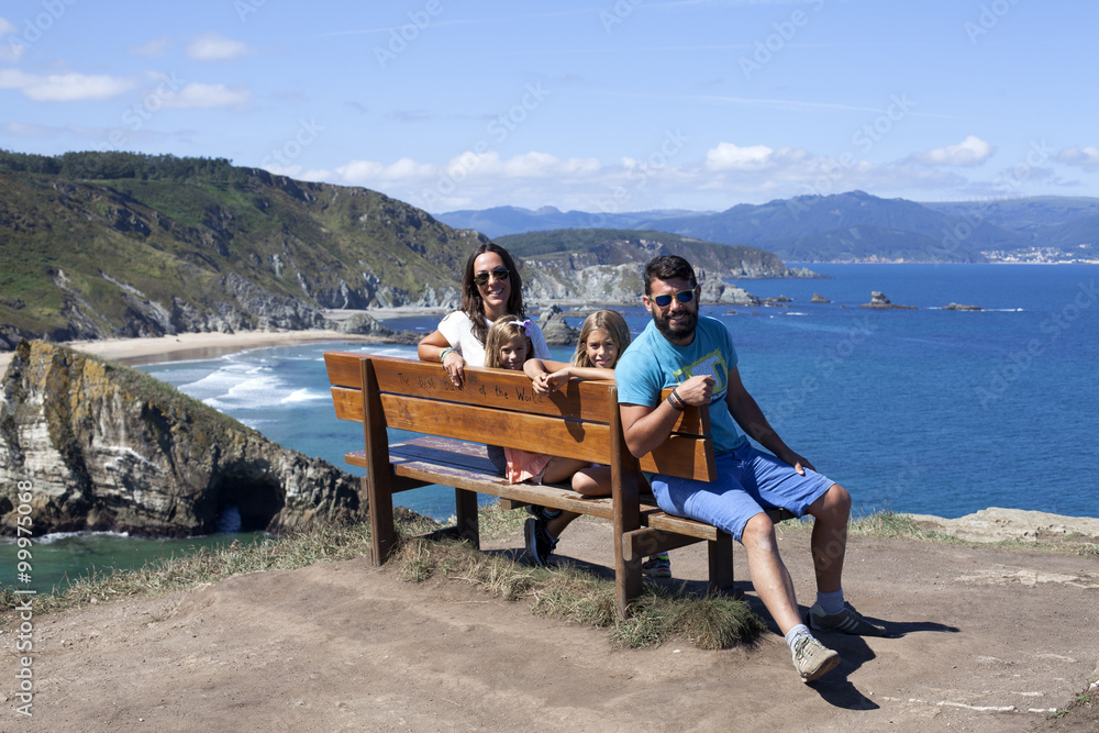 Familia sentada en banco junto a acantilado marino