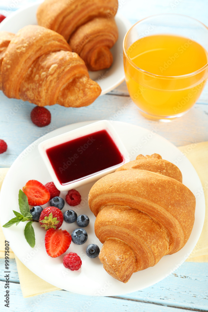 Fresh tasty croissants with berries on blue wooden background Fresh tasty croissants with berries on blue wooden background