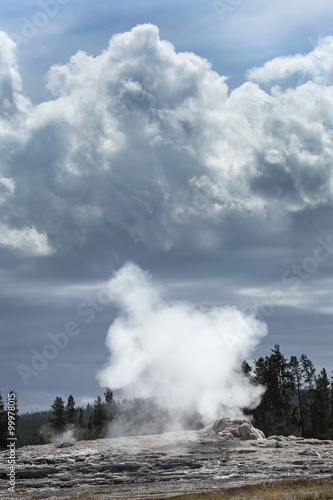 Steam and black clouds over Old Faithful geyser, Yellowstone, Wyoming.