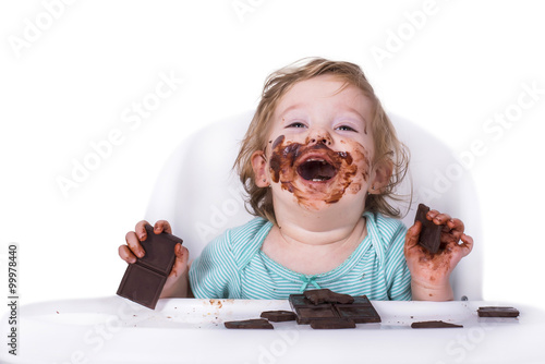 Adorable kid eating chocolate with face covered in chocolate