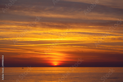 Beautiful sunset on the Mediterranean sea in Cyprus with a fishing boat silhouette on the horizon
