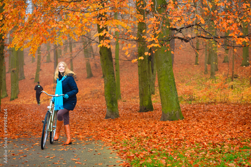 Happy active woman riding bike in autumn park. Happy active woman riding bike in autumn park.