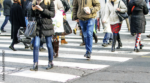 Motion blurred pedestrians crossing sunlit street