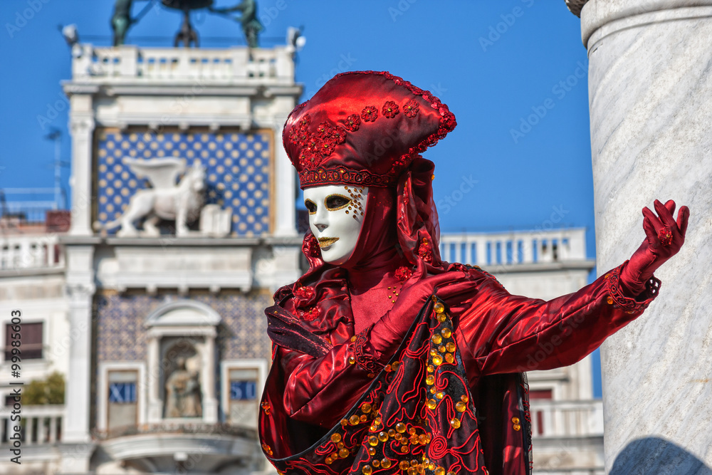Venetian Mask dressed in red Carnival costume posing in Saint Mark's Square Venice, Italy