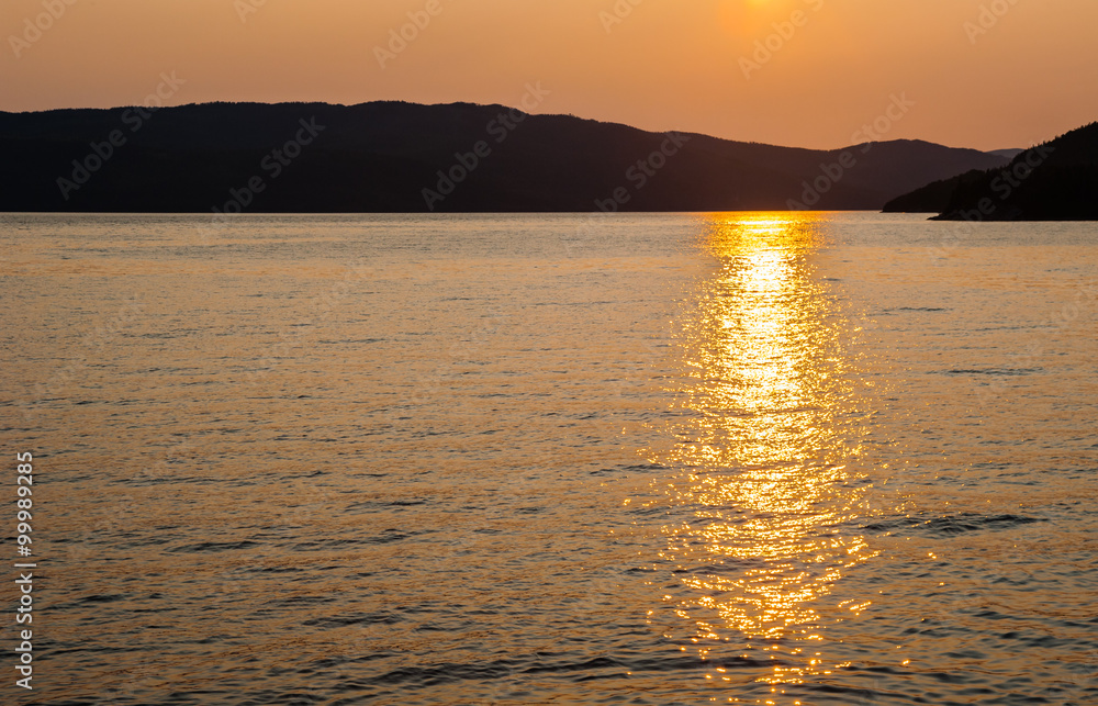 Silhouette of hills against water reflecting sunset