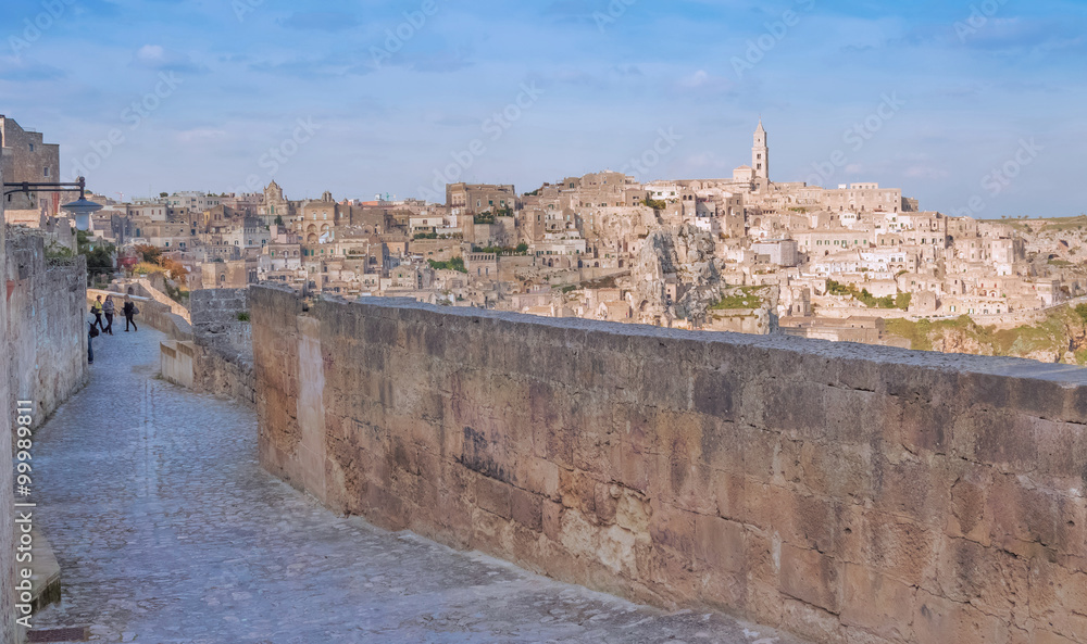 panoramic view of typical stones and church of Matera shot from typical old street, under blu sky