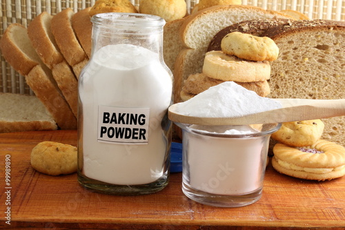 baking powder in a glass jar and wooden spoon with cookie and bread photo