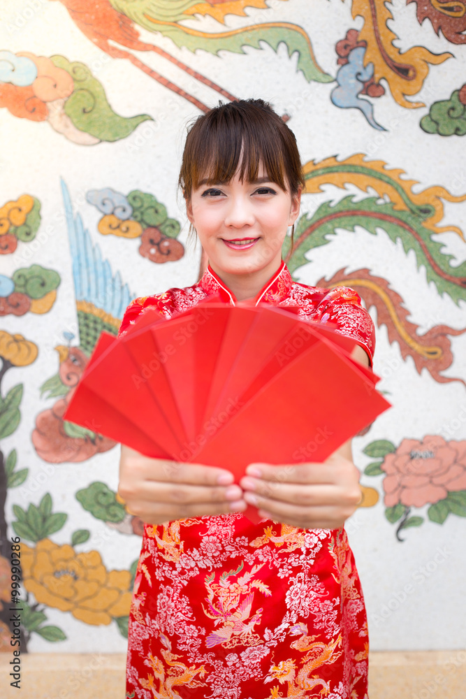 Happy chinese new year,Cute smiling Asian woman dress traditional cheongsam and qipao holding red envelopes ang pow or red packet monetary gift card on chinese pattern traditional background