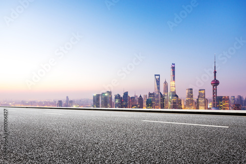 empty asphalt road and cityscape in blue sky at dawn
