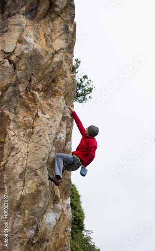 Young male climber hanging on a cliff with a rope.