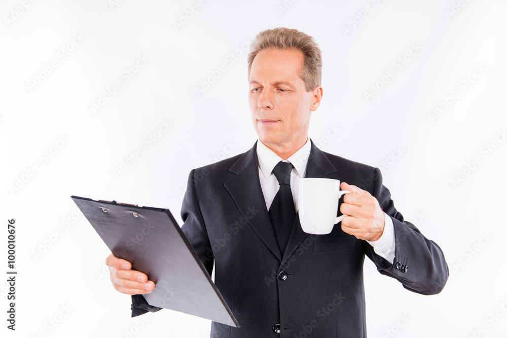 Confident businessman reading information in a folder and holdin Confident businessman reading information in a folder and holdin