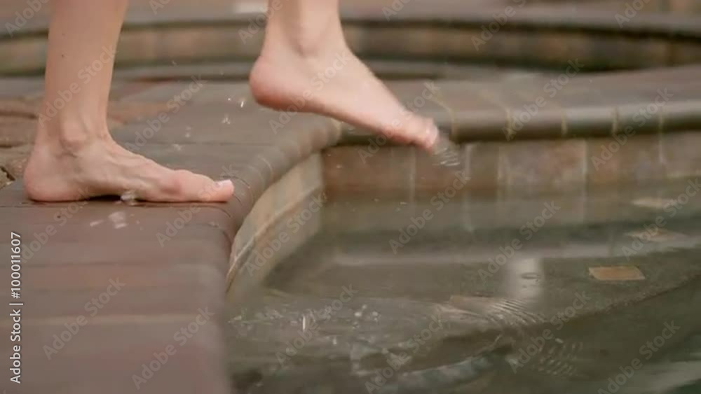 A woman testing the water in a pool with her toes and then stepping in, in slow motion A woman testing the water in a pool with her toes and then stepping in, in slow motion
