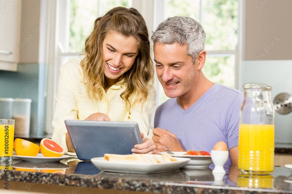Happy couple using tablet and having breakfast Happy couple using tablet and having breakfast