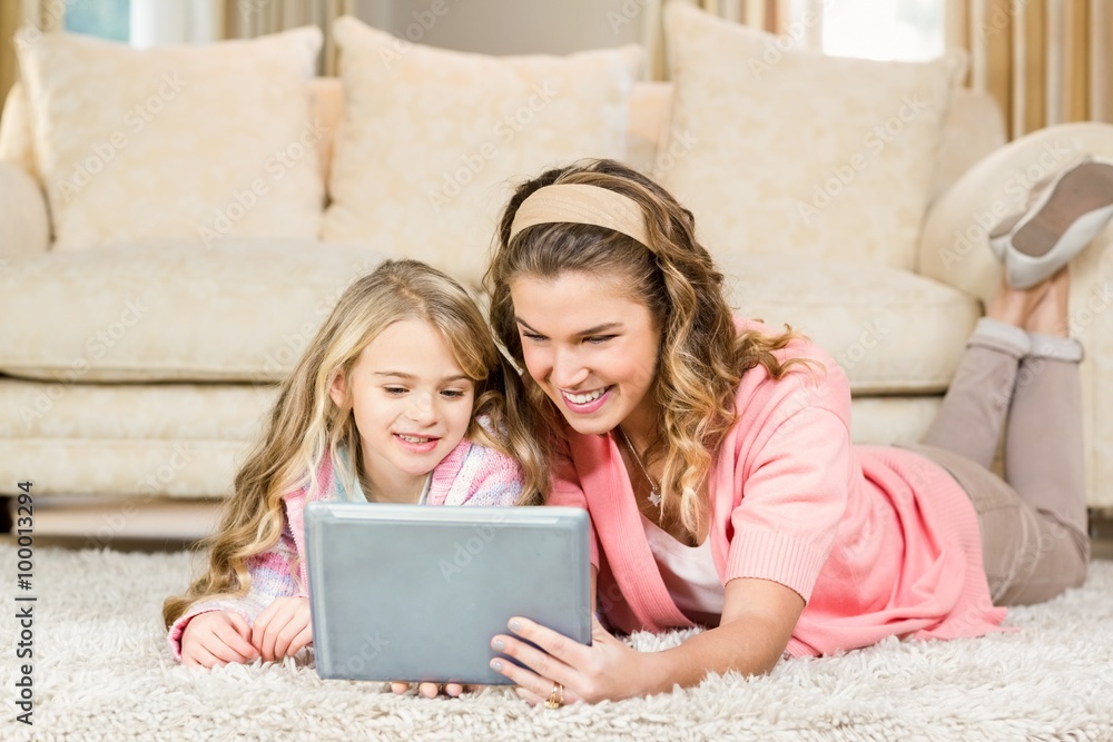 Mom and daughter lying on the floor using a tablet Mom and daughter lying on the floor using a tablet