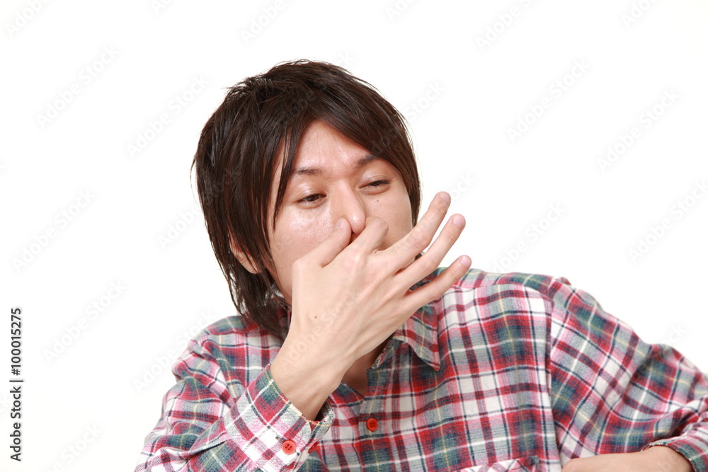 Japanese man holding his nose because of a bad smell Japanese man holding his nose because of a bad smell