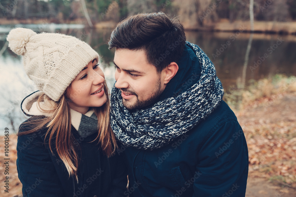Fototapeta premium happy couple in warm knitted hat and scarf walking outdoor in autumn forest, cozy mood