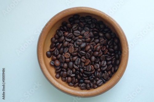 Roasted coffee beans in the wooden plate on a blue background