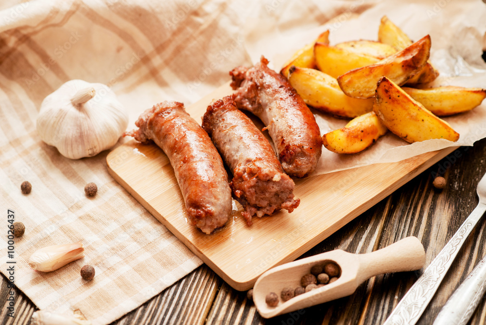 meat with vegetables , fried homemade sausage with roasted potatoes with garlic and pepper on a wooden background meat with vegetables , fried homemade sausage with roasted potatoes with garlic and pepper on a wooden background