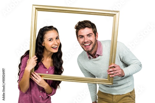 Portrait of happy couple holding picture frame 