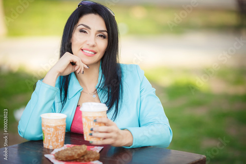 Beautiful middle age woman drinking coffe in cafe outdoor
