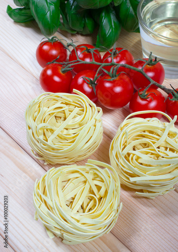 Raw homemade pasta and ingredients for pasta with tomatoes and basil.