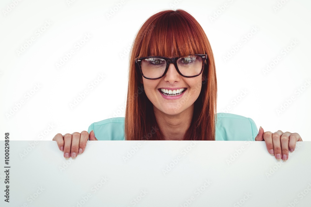 Smiling hipster woman behind a white card Smiling hipster woman behind a white card