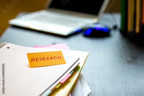 Research; Stack of Documents and Laptop at working Desk.