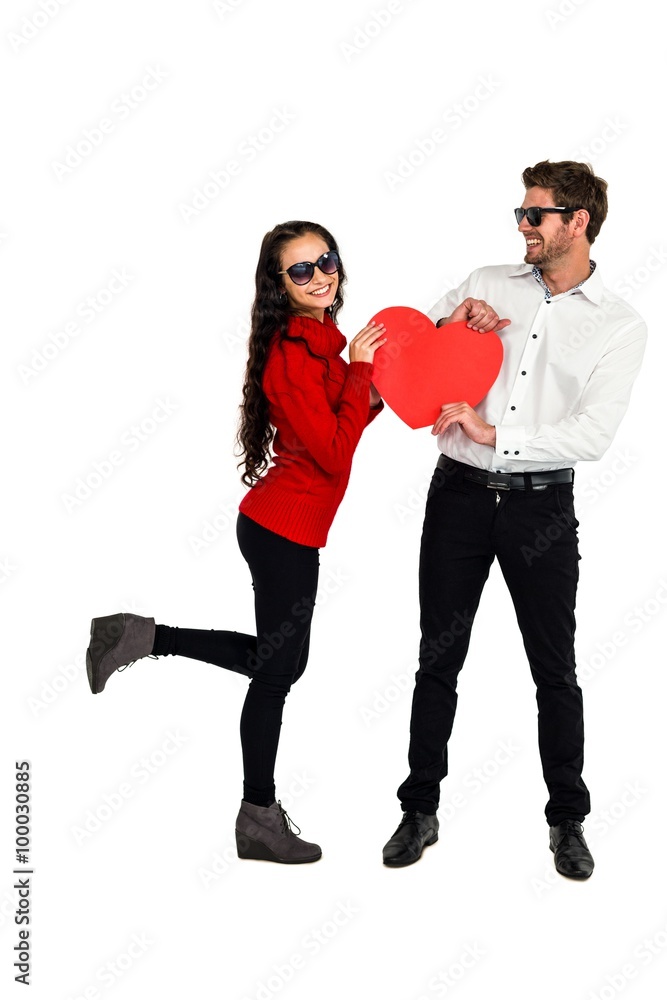 Smiling couple with sunglasses holding paper heart Smiling couple with sunglasses holding paper heart