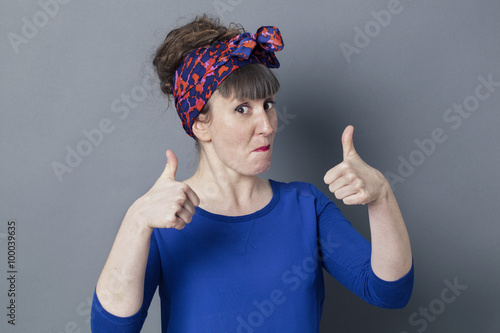 optimism concept - impressed 30s woman smiling with two thumbs up for cool happiness, studio grey background