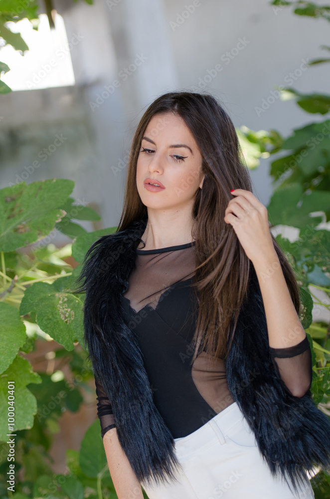 Foto de Petite young woman with very long hair wear bodysuits and lamb fur  vest do Stock