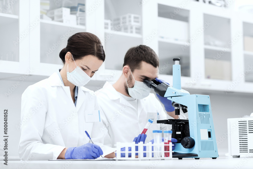 scientists with clipboard and microscope in lab scientists with clipboard and microscope in lab