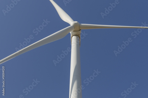 Wind turbine producing alternative energy on blue sky