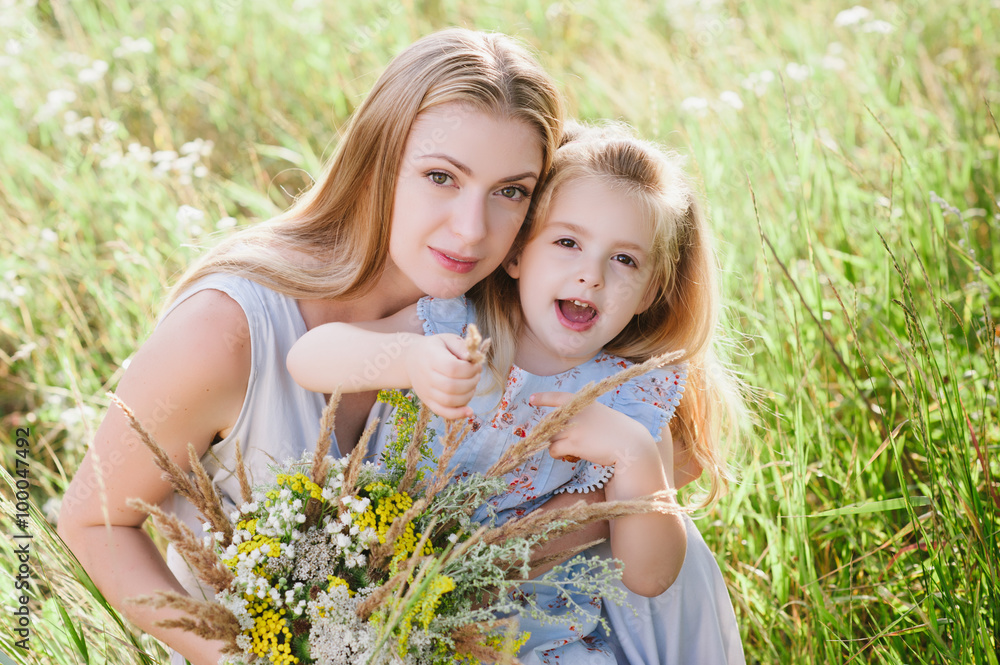 Mom and daughter in nature with a bouquet of wild flowers, family, family values, childhood, lifestyle Mom and daughter in nature with a bouquet of wild flowers, family, family values, childhood, lifestyle