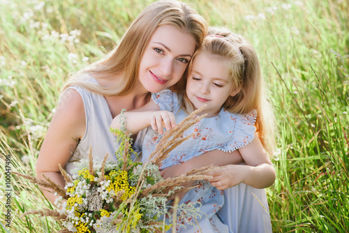 Mom and daughter in nature with a bouquet of wild flowers, family, family values, childhood, lifestyle