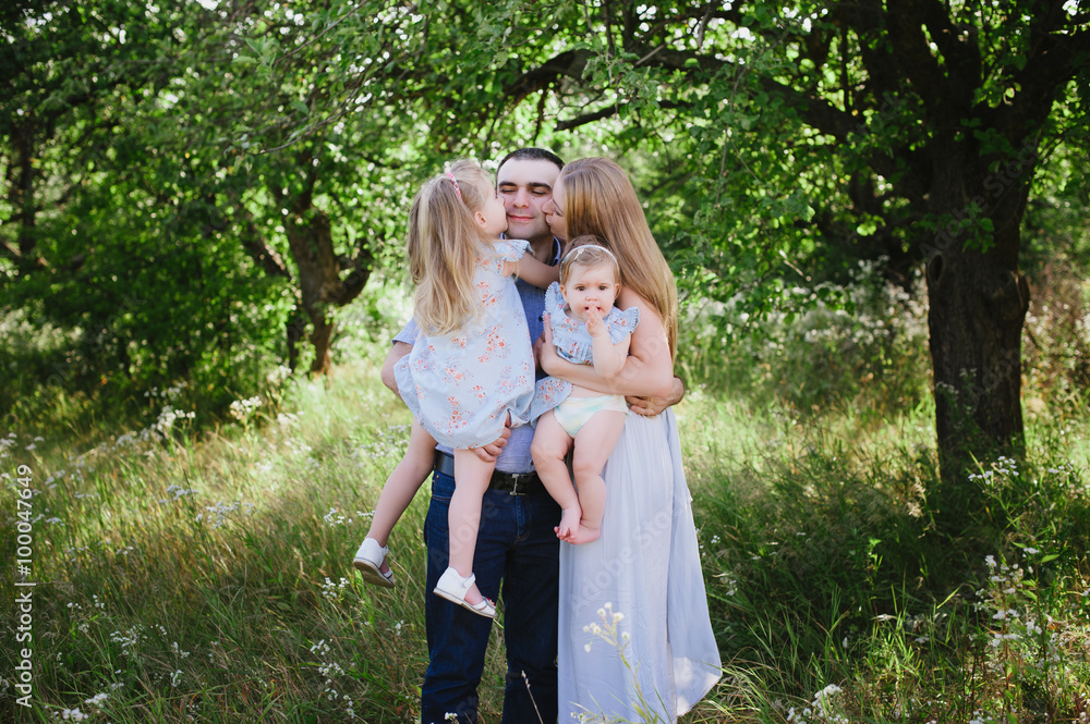 Mom and dad playing on the nature and hugging two daughters, family, childhood, family values, life style Mom and dad playing on the nature and hugging two daughters, family, childhood, family values, life style