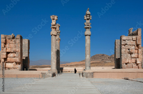 Silhouette of a woman in a Muslim hijab in between ruined columns of palace in Persepolis